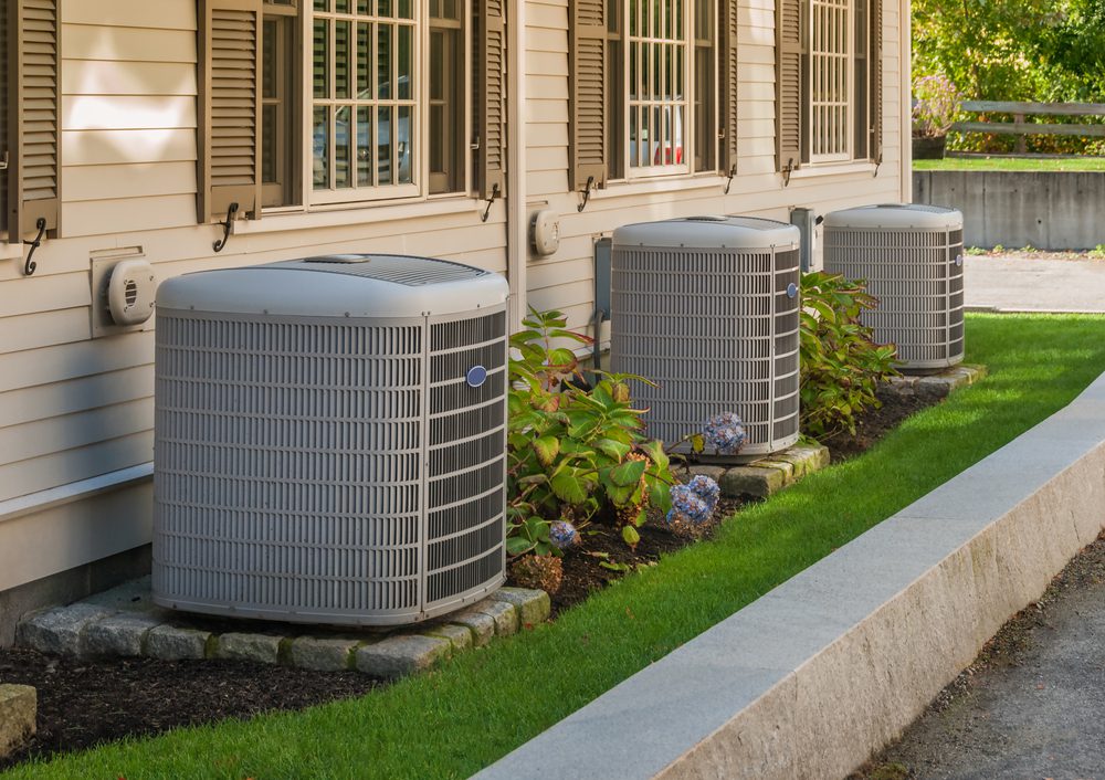 Three air conditioners are sitting outside of a building.