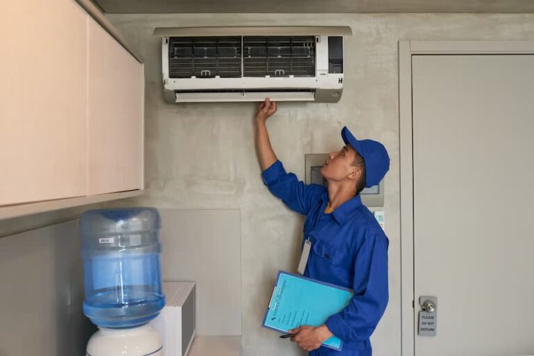 A man in blue shirt holding a box near air conditioner.