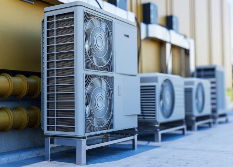 A row of air conditioners sitting on top of concrete.