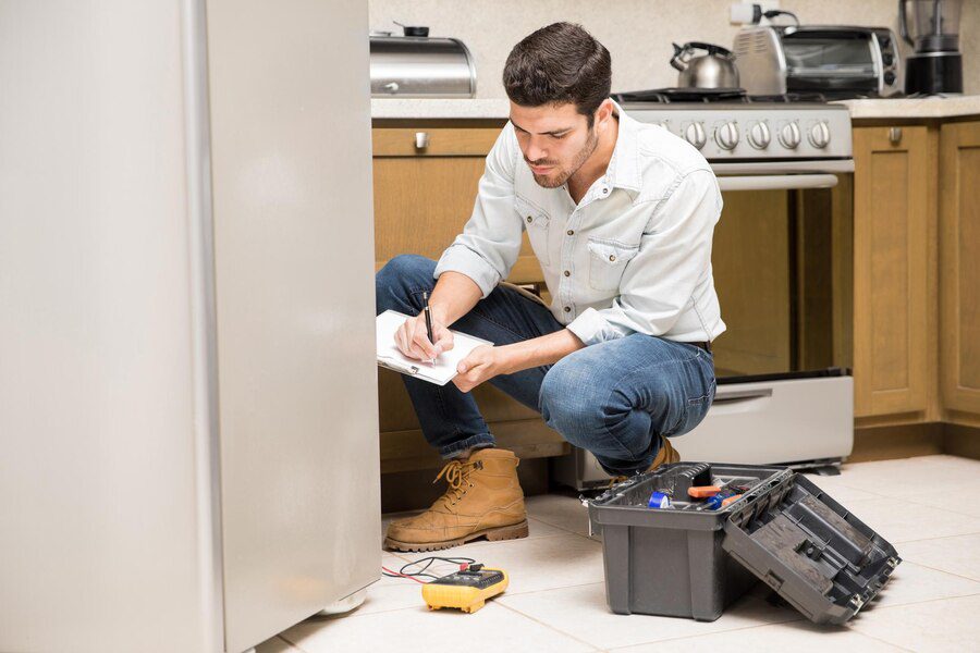 A man is writing on paper in the kitchen.