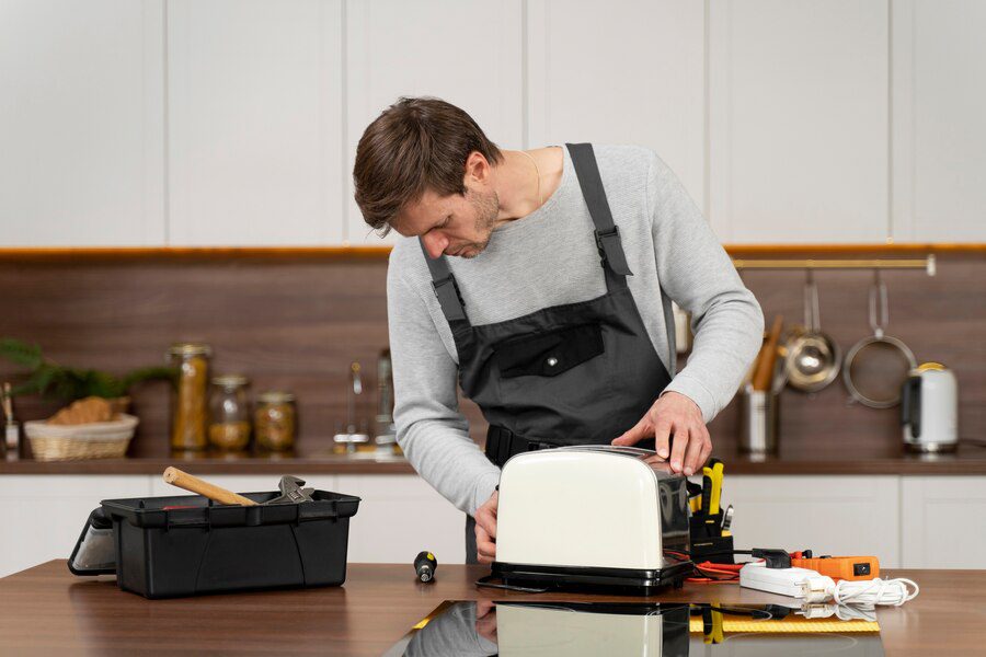 A man in an apron is working on a toaster.