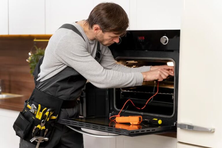 A man in an apron is fixing the oven.