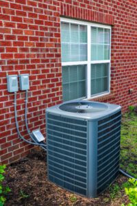 A residential air conditioner unit sitting outside of a building.