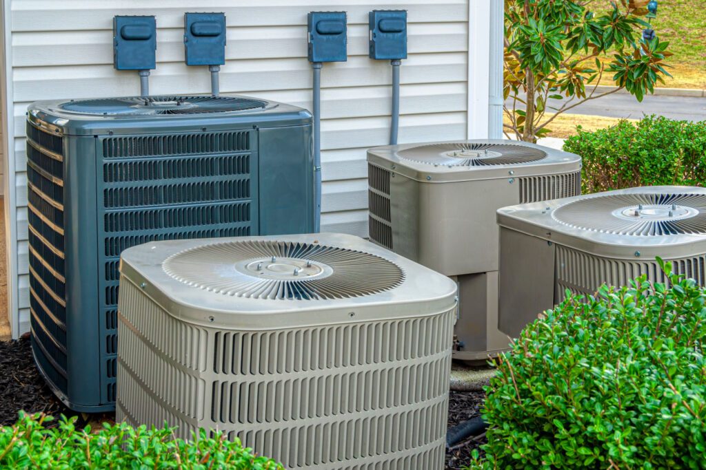 A bunch of air conditioners sitting outside in the yard