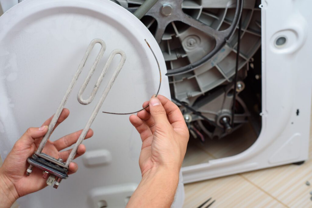 A person is holding some wires in front of an appliance.