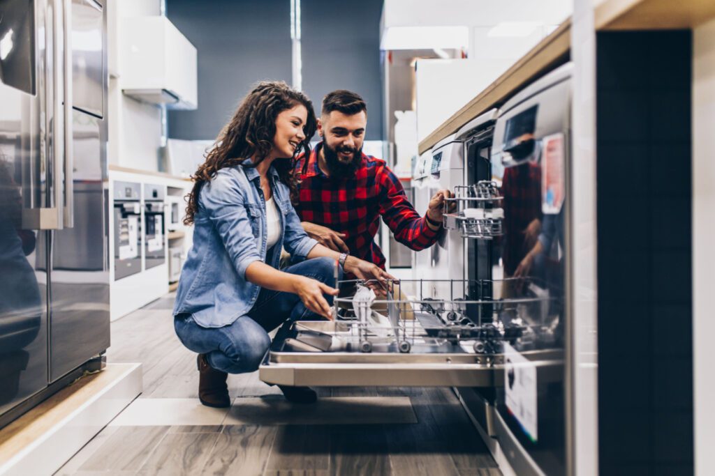 A man and woman looking at the dishwasher.